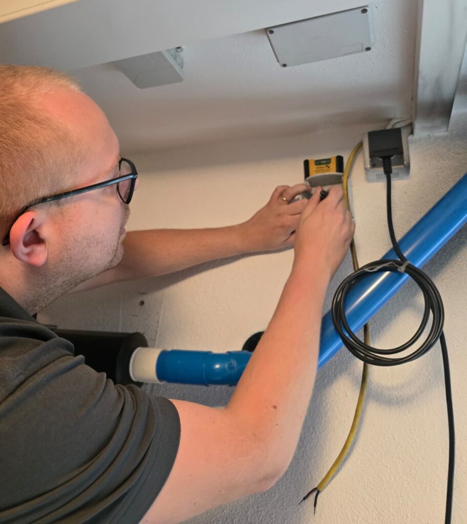 Unsere Dienstleistungen Geschäftsführer Simon Hofbauer bei der Arbeit am Schaltschrank.