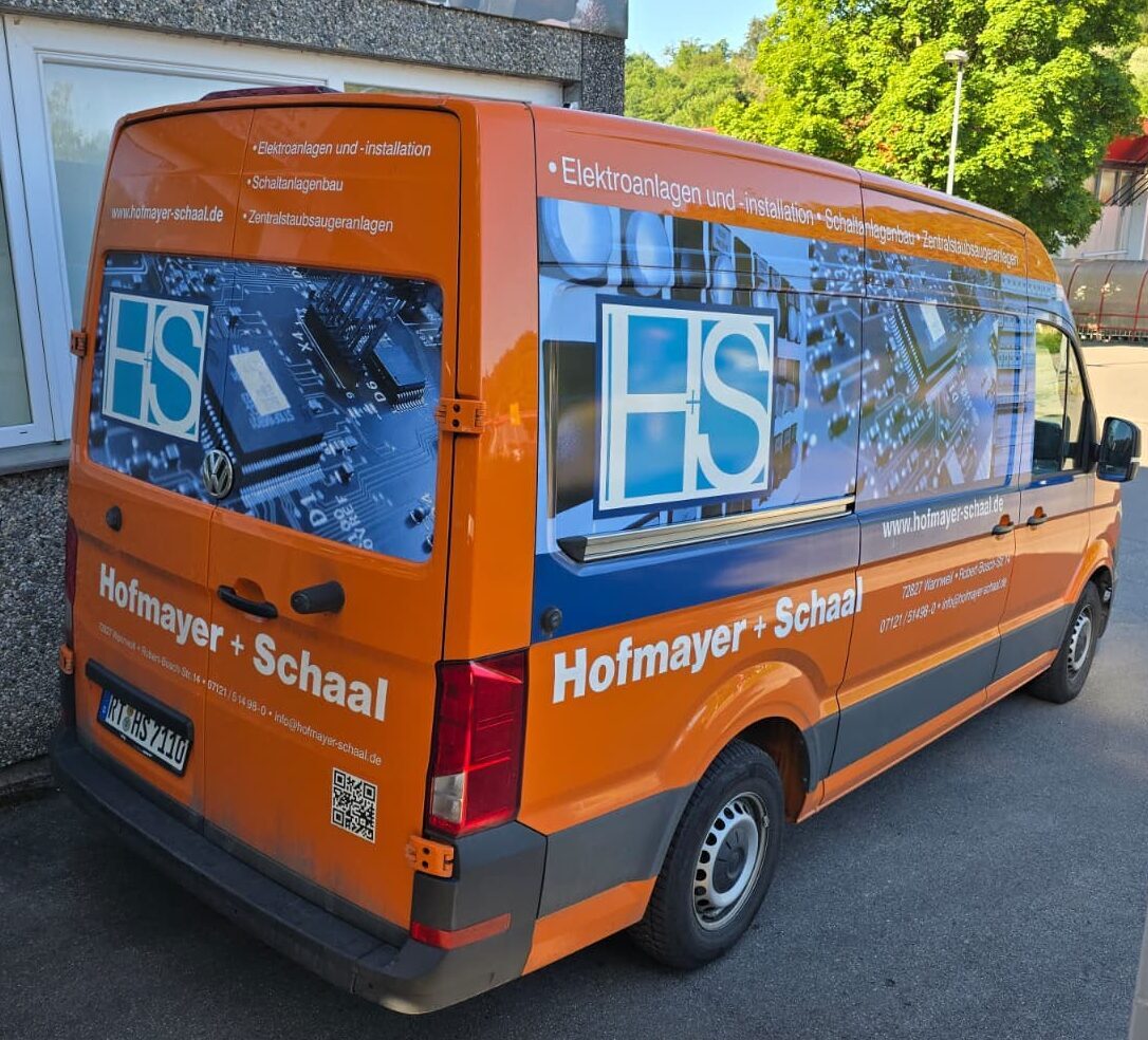 Ein orangener Geschäftsbus von Hofmayer + Schaal. Der Bus steht vor dem Betriebsgebäude.